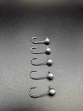 Five unpainted round-head micro jig heads arranged in a row on a dark background